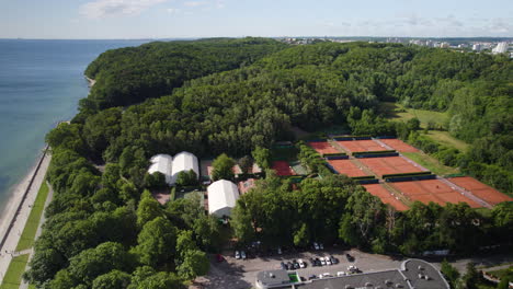 Aerial-View-of-Seaside-Boulevard-Area-in-Gdynia-City-Poland,-Tennis-Outdoor-Clay-Courts-Surrounded-by-Beautiful-Nature-Forest-Topped-Lands-and-Hills-along-the-Seashore,-Coastal-Landscape