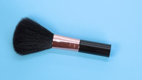 Black-makeup-brush-detail-macro-shot,-rotating-motion-on-blue-surface-background