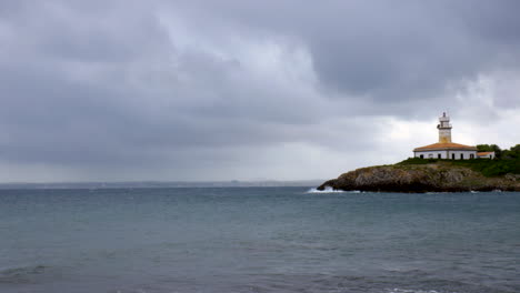 Waves-hitting-the-rocks-on-an-island-with-a-lighthouse-on-a-cloudy-autumn-day