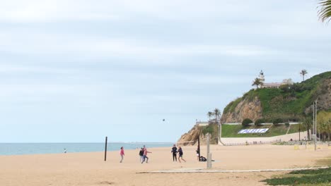 Group-of-friends-playing-beach-volleyball-in-Calella-on-a-cloudy-day