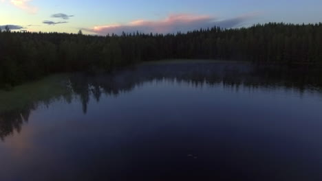 Aerial-video-of-a-remote-misty-forest-lake-by-dusk-in-borealis-wilderness