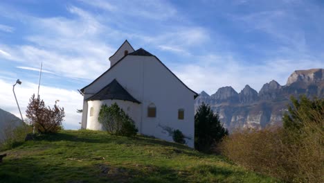 Schwenk-Von-Einem-Bergpanorama-Auf-Eine-Alte-Kleine-Kapelle-Im-Herbst-In-Der-Schweiz