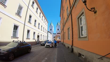 Car-and-bike-passing-through-narrow-street-in-Passau,-Germany-old-town,-everyday-life