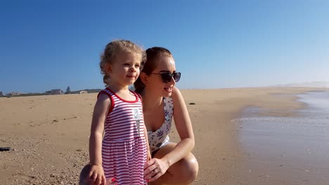 Mother-and-daughter-is-on-the-beach-looking-at-the-waves