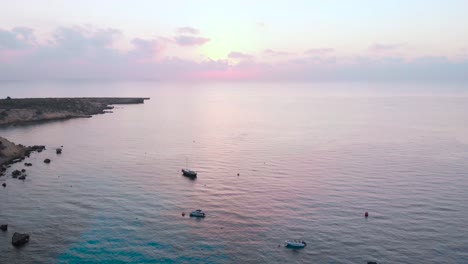 Aerial-panning-shot-over-boats-anchored-in-Konnos-Bay-at-dusk