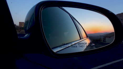 A-beautiful-usa-sunset-can-be-seen-through-the-side-mirror-reflection-of-a-car