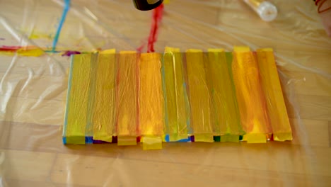 A-woman-using-painters-tape-to-finish-her-colorful-stripes-on-a-canvas