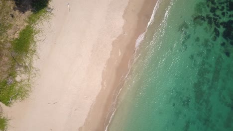 Aerial-shot-of-turquoise-waters-washing-up-at-white-sandy-beach-Thailand---camera-rotating-with-pedestal-down---zoom