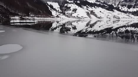 Close-flight-over-ice-and-water-past-a-raft-on-a-mountain-lake-in-Switzerland