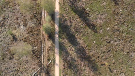 Aerial-top-down-view-of-a-couple-walking-along-a-path-through-a-moorland-landscape-with-the-view-changing-to-reveal-the-path-in-front-of-the-couple