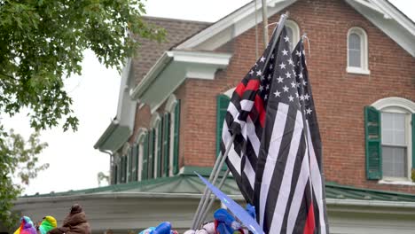 American-flags-set-against-an-old-building-in-a-small-town-at-a-festival-with-some-of-the-flags-having-the-thin-red-line-which-honors-fire-fighters