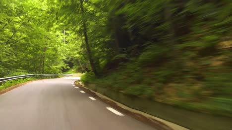 Driving-on-a-winding-road-in-a-forest,-Bucegi-Mountains,-Rumania