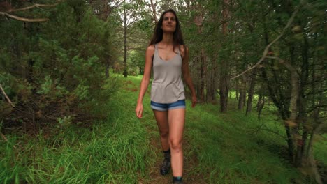 Looking-back-at-a-tall-beautiful-brunette-woman-on-a-hike-through-a-thick-green-forest-in-Barcelonnette,-France