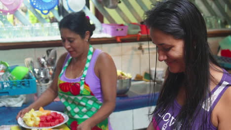 Dos-Mujeres-Costarricenses-Sonriendo-Y-Trabajando-Juntas-En-Una-Cocina-Preparando-Frutas-Y-Verduras-Coloridas
