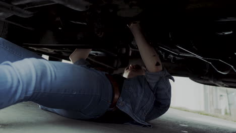 Woman-in-early-20s-checking-under-the-hood-of-a-truck-and-going-under-the-truck-to-find-and-fix-mechanical-problem