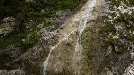 Palenk-waterfall-in-Logarska-valley,-Slovenia,-alpine-creek-cascading-over-rocks,-HD,-low-angle-to-high-angle,-pan-up