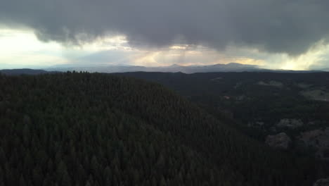 Aerial-View-of-Storm-Clouds-Looming-in-the-Distance-in-the-Forested-Mountains-of-Colorado,-High-Angle,-Forward-Motion