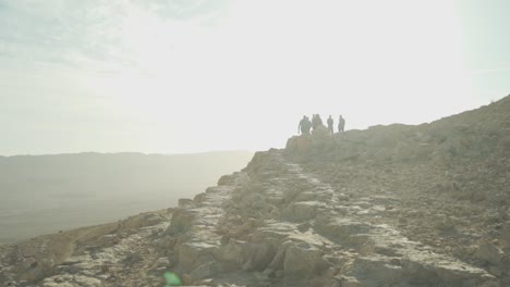 Grupo-De-Viajeros-Caminando-Sobre-La-Cresta-Del-Desierto-Bajo-El-Sol