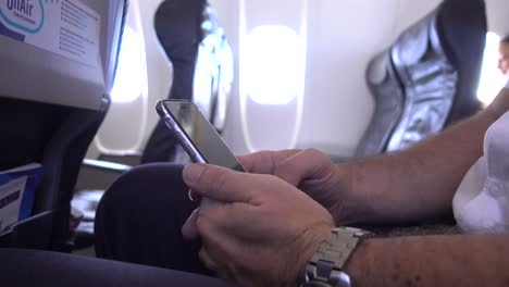 Business-Man-Travelling-in-Aircraft-Using-Mobile-Phone-during-Flight,-scrolling-and-typing-and-doing-hand-gestures