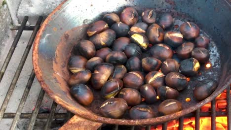 Chestnuts-roasted-on-open-fire,-seasonal-delicacy,-harvest,-1920-HD,-holiday-favorite-food,-close-up,-roasting-in-iron-pan,-crane-shot-low-to-high-revealing-chestnuts