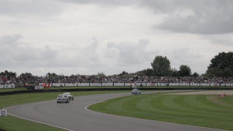 Track-side-view-of-old-cars-racing-side-by-side-into-turn-one-at-the-Goodwood-Revival-Car-Festival