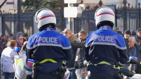 Two-police-officers-from-the-motocycle-division-wearing-a-helmet-and-a-blue-uniform-observe-a-crowd-during-a-yellow-jacket-demonstration-in-Marseille,-south-of-France