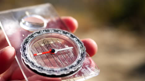 Close-up-on-the-needle-spinning-of-a-magnetic-compass-finding-north-on-a-hike-to-stay-on-the-trail-and-not-get-lost-in-the-wilderness