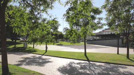 Städtischer-Stadtpark-Bäume-Bürgersteig-Mittagssonne-Sonnig-Gras-Blauer-Himmel-Portugal-Schieberbewegung