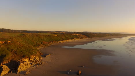 Drone-descending-over-Whiskey-Run,-a-beach-near-Bandon-at-the-Southern-Oregon-coast-during-sunset