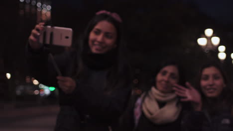 Slow-motion-clip-of-a-group-of-three-female-friends-while-using-a-selfie-stick-to-take-a-photo-in-Madrid,-Spain