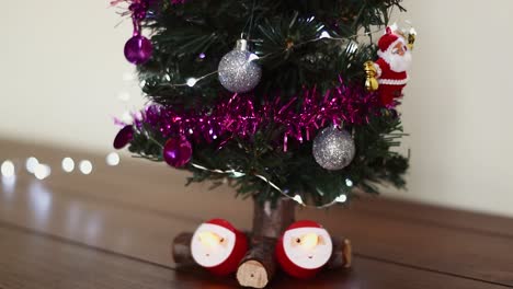 Tilt-up-shot-of-little-decorated-green-Christmas-tree-and-two-electric-candles