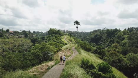 A-young-couple-is-walking-along-a-narrow-path-in-the-jungle