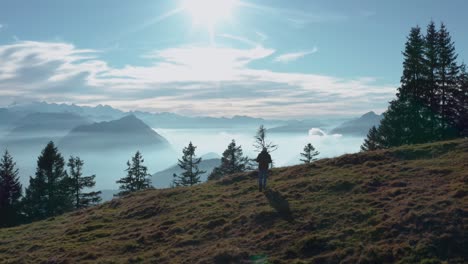 Guy-Caminando-Sobre-La-Cresta-De-Una-Montaña-Mirando-Hacia-El-Hermoso-Paisaje-De-Montaña-Con-Lago-Cubierto-De-Niebla-Soleados-Alpes-Suizos-Rigi