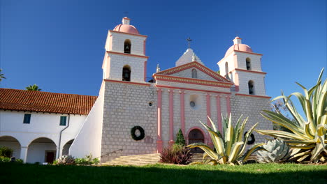 Blick-Nach-Oben-Auf-Das-Gebäude-Der-Spanischen-Mission-Santa-Barbara-In-Kalifornien-Mit-Pflanzen-Auf-Einer-Wiese,-Rutsche-Nach-Links