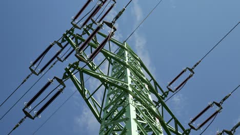 High-voltage-power-lines-and-pylon,-low-angle-shot-with-blue-sky-in-the-background---sliding-right