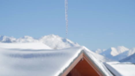 Single-icicle-melting-with-clear-blue-sky-and-mountain-in-background