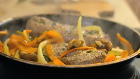 Close-up-of-frying-meat-and-vegetables-in-a-pan,-steam-rising-from-food