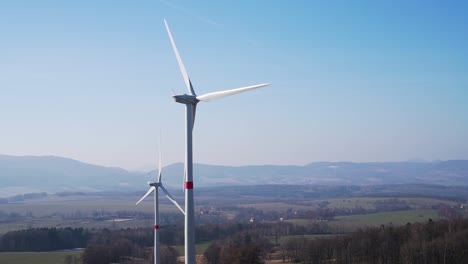 Windkraftanlagen-Im-Feld-Mit-Hügeln-Im-Hintergrund-–-Panoramaaufnahme