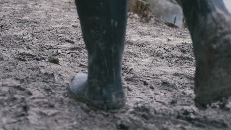Muddy-boots-walking-along-a-muddy-path,-rear-view,-slow-motion