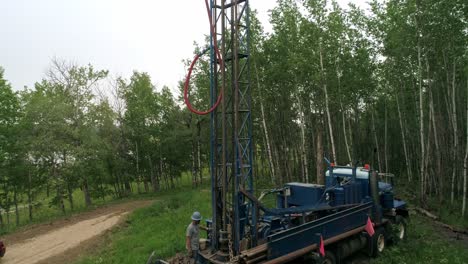 Raised-aerial-view-of-water-well-drilling-rig-derrick-and-operator-drilling-in-a-rural-area
