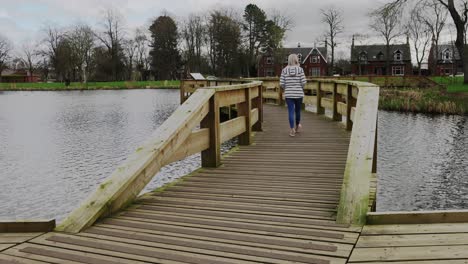 A-young-woman-walks-over-a-bridge-in-a-local-park
