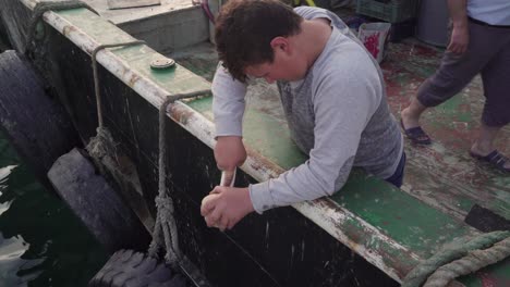 A-young-boy-cleaning-a-seashell-at-the-boat