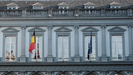 Banderas-De-La-Unión-Europea-Y-Belga-Ondeando-En-El-Viento-En-Un-Edificio-Antiguo-En-Bruselas,-Bélgica