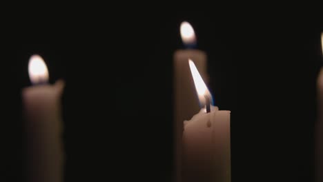 Four-white-candles-lit-and-a-fast-pan-across-them-in-slow-motion