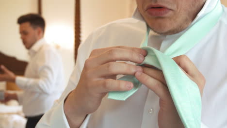 Man-tying-his-tie-on-wedding-day