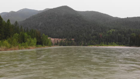 Luftaufnahme-Des-Flathead-River-In-Montana,-Kamera-Bewegt-Sich-Rückwärts-In-Der-Nähe-Des-Wassers,-Berge-Und-Kiefernwald-Im-Hintergrundparallaxe