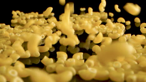 French-pasta-macaroni-coquillettes-Falling-on-black-table---Slow-Motion