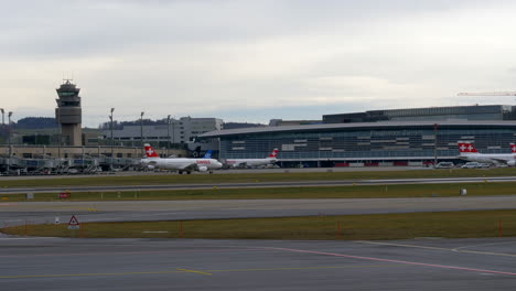 An-airline-aircraft-taxiing-to-the-gate-in-front-of-the-terminal-at-a-busy-airport