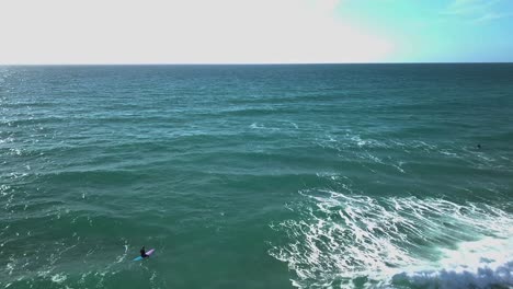 Surfistas-Flotando-Encima-De-Olas-Claras-Rompiendo