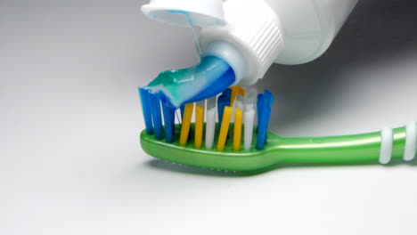 Zahnpasta-Wird-Auf-Eine-Grüne-Zahnbürste-Aufgetragen